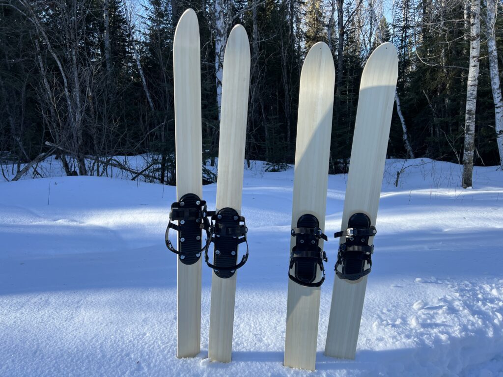 Two pair of LAT 68 back country skis with background of snow in forest