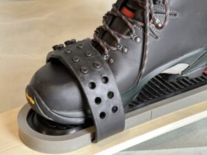 A boot inside plastic binding with plastic frame mounted on a ski.