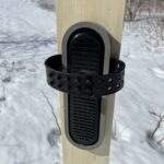 Plastic binding with plastic frame mounted on a ski placed on snow.