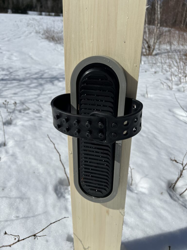 Plastic binding with plastic frame mounted on a ski placed on snow.