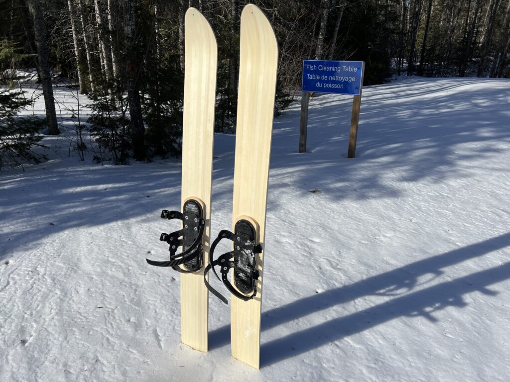 Three strap ski binding mounted on a pair of skis placed in snow.