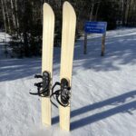 Three strap ski binding mounted on a pair of skis placed in snow.