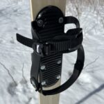 Two strap ski binding mounted on a ski placed in snow.